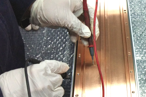 電筆在銅板上測量，體現上海駿材在磁控濺射組件領域的工程技術能力